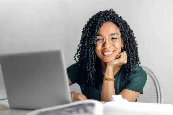 Mulher sorrindo diante de um notebook