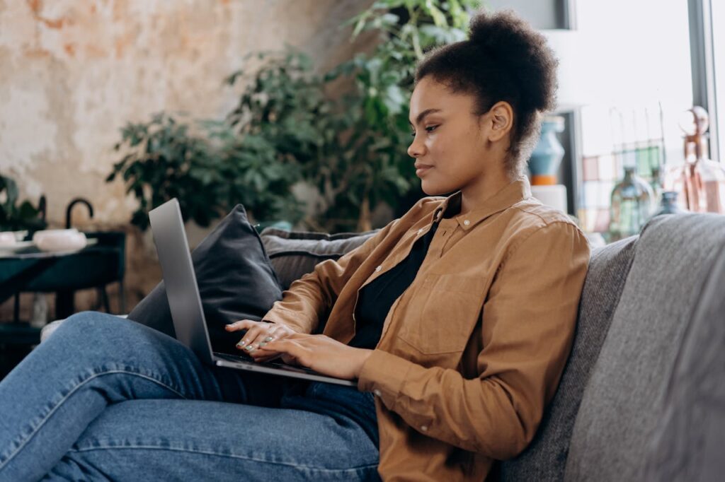 Mulher sentada com notebook no colo, fazendo terapia online.